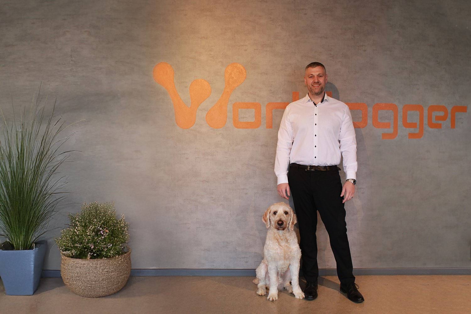 Noël Birkholm Worklogger ejer med hund foran logo